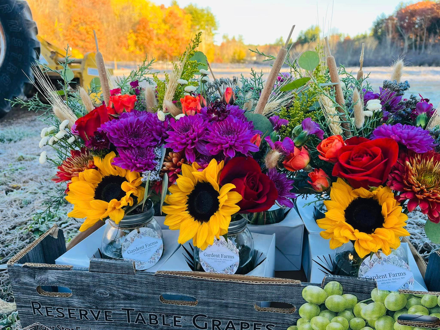 Photograph of several beautiful floral arrangements on a table including sunflowers, roses, dahlias, and grasses from Gardent Farms.  