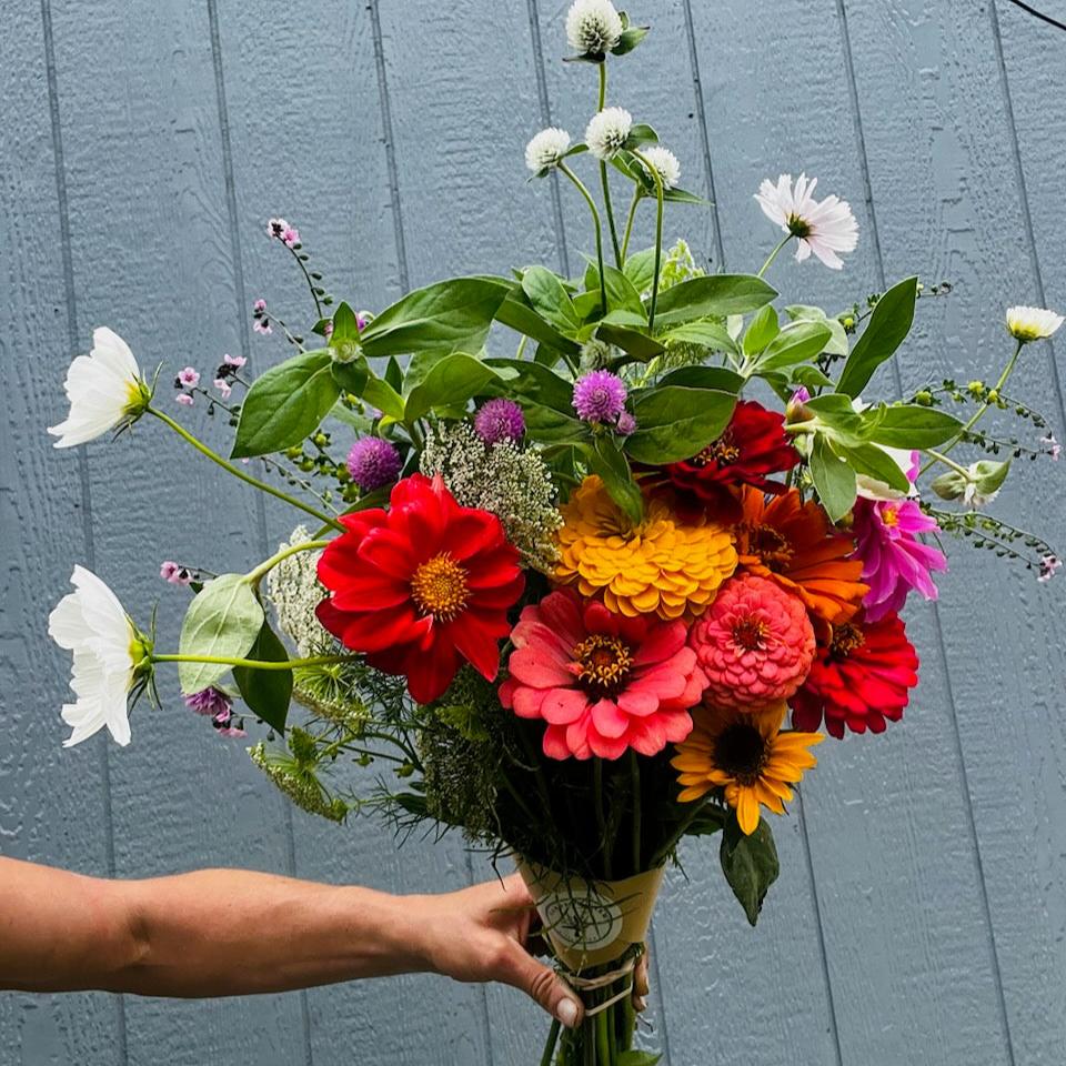 Large, late summer floral bouquet in vibrant colors displayed in front of a barn wall.