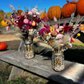 Multicolor dried floral arrangements in  mason jars with colored ornamental corn filler.