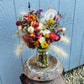 A large arrangement of dried flowers in a mason jar with ornamental corn fill.