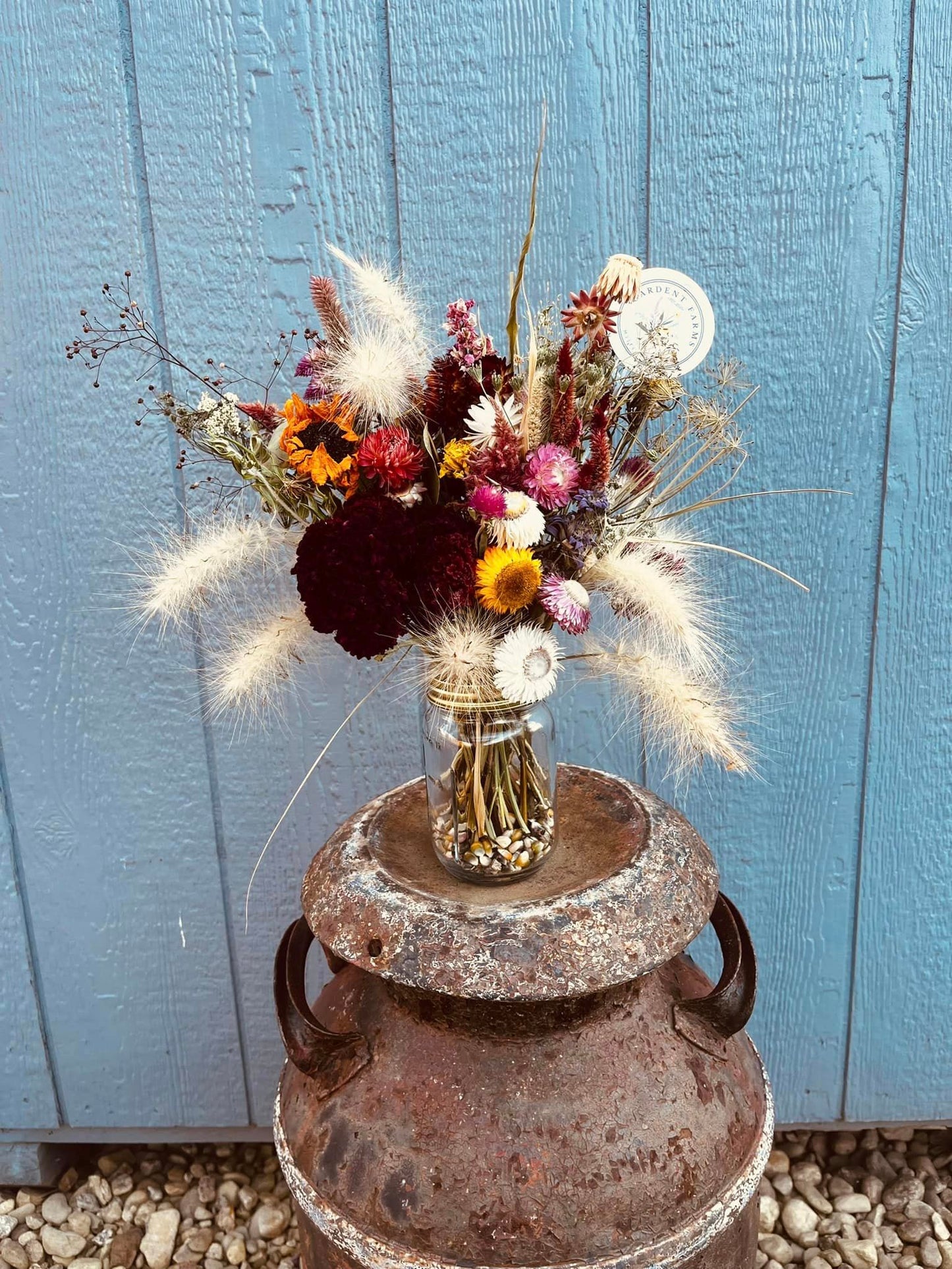 A 16oz mason jar filled with dried flowers on display at a farm.