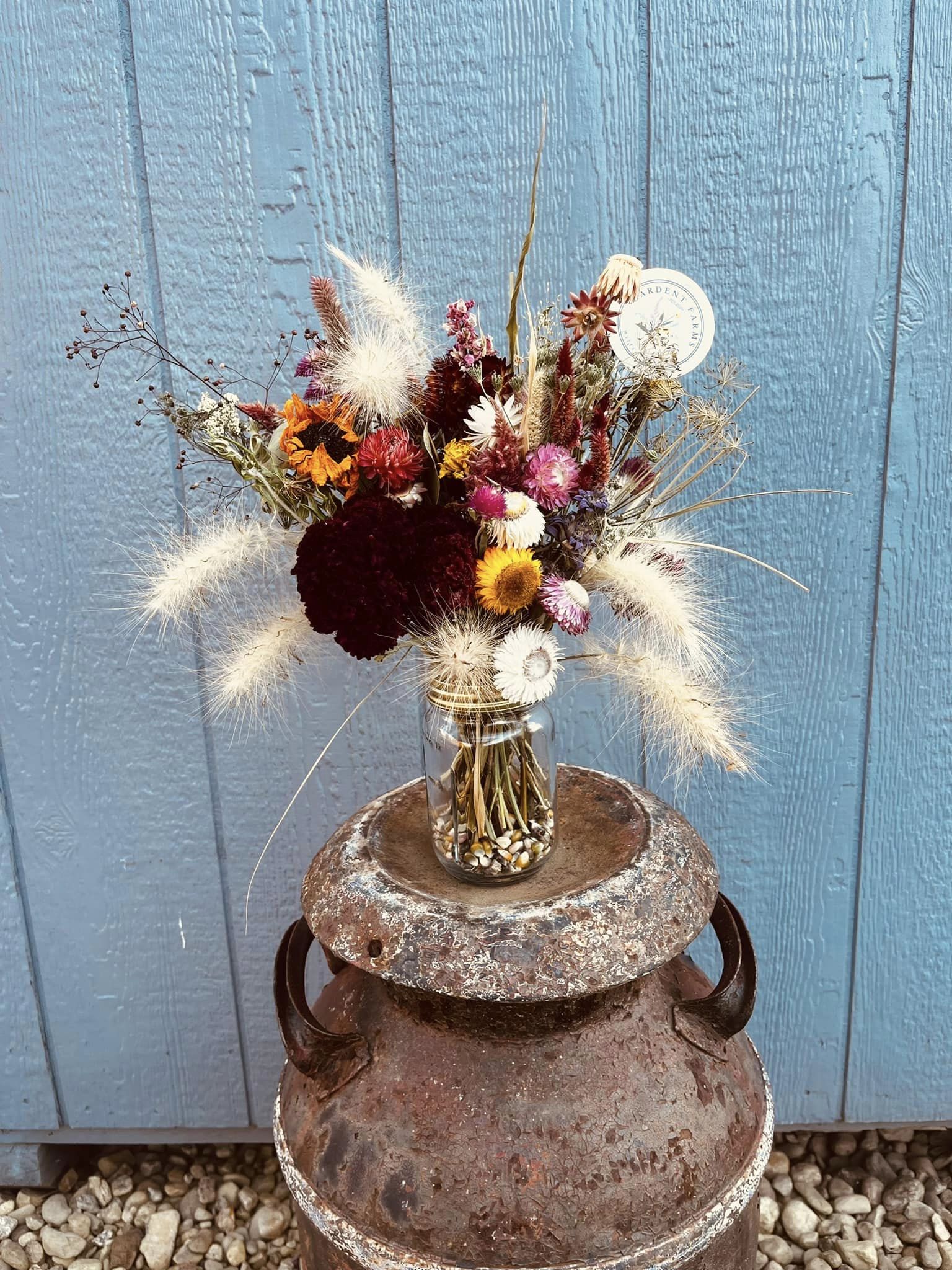 A 16oz mason jar filled with dried flowers on display at a farm.